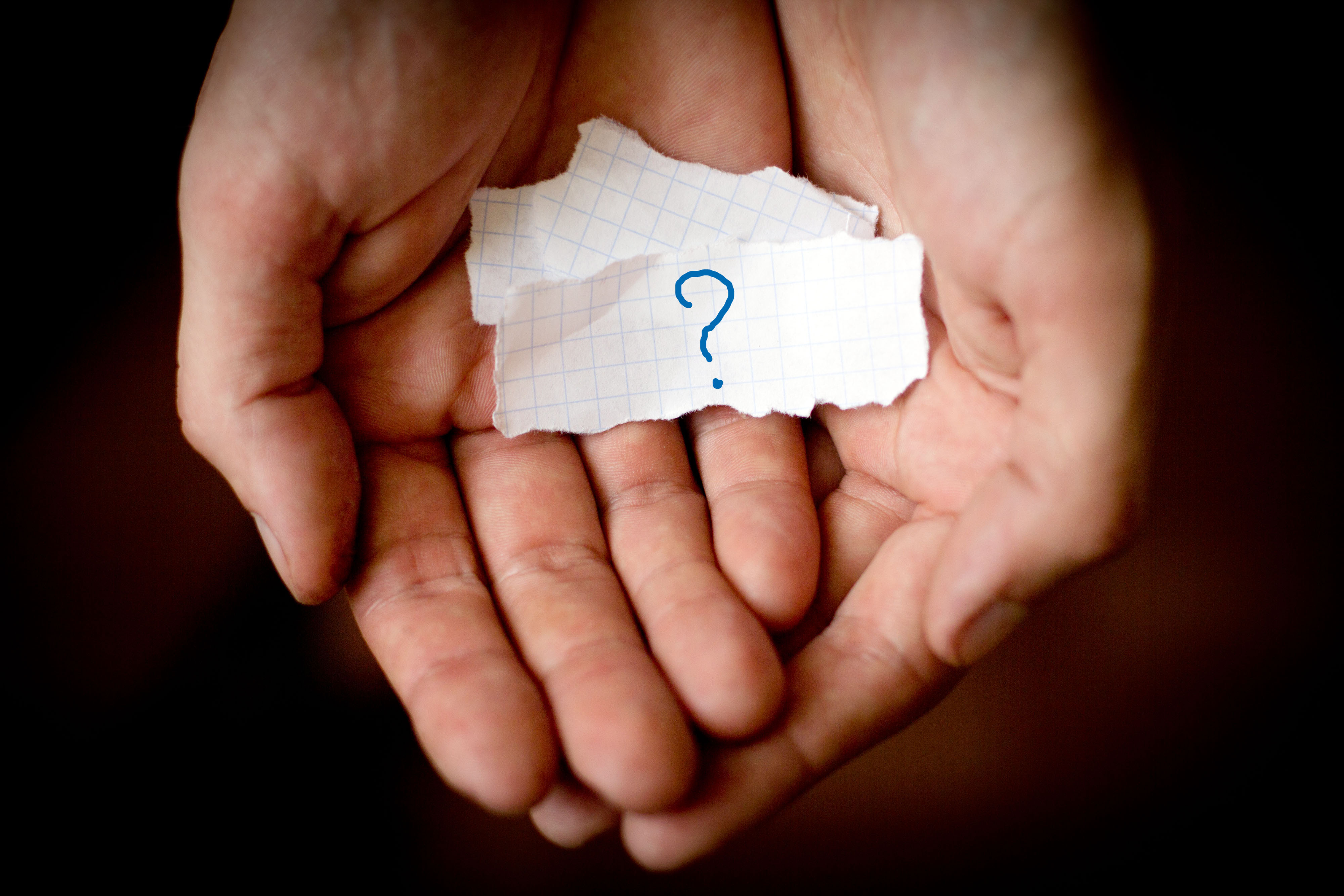 Male hands holding scraps of notebook on which is drawn a questi